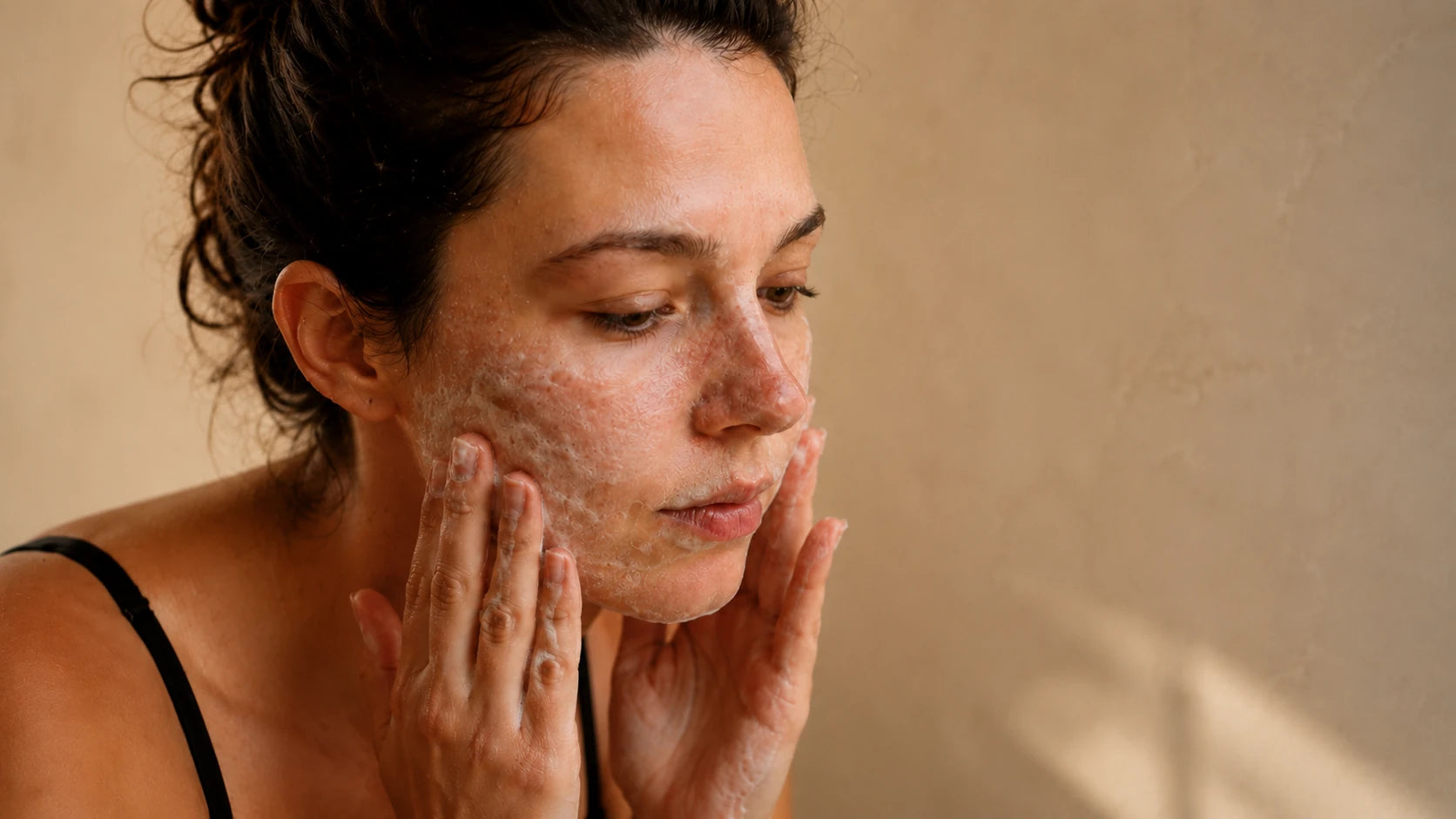 A woman cleansing her face with a gentle cleanser at a stone basin, representing the Truth Treatment Systems cleansing and prep step